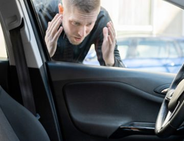 Man peering into his car window that he locked himself out of.