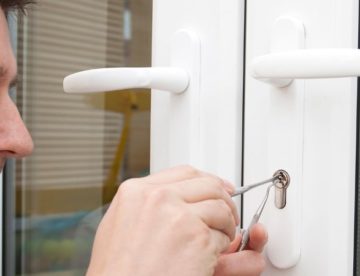 Residential locksmith using tools on glass doors