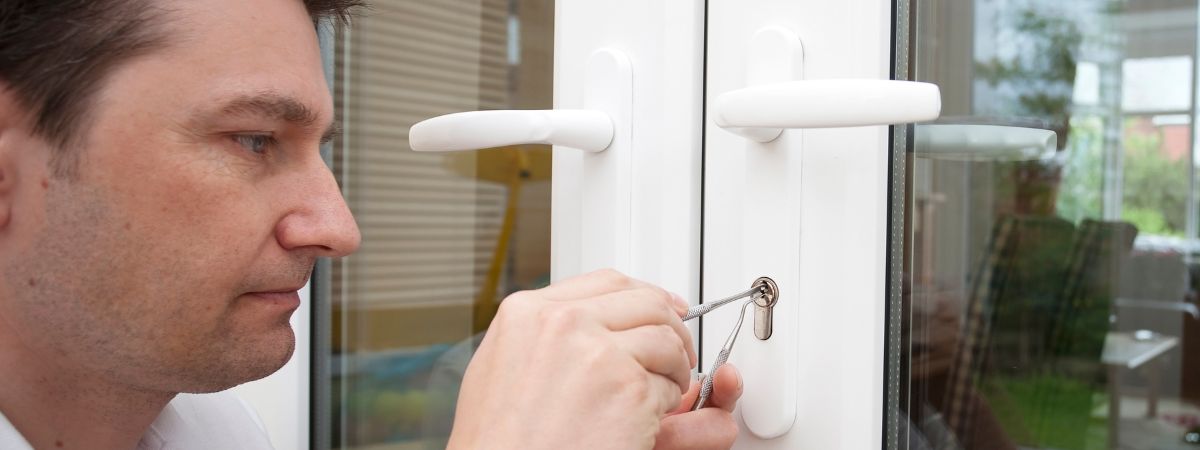 Residential locksmith using tools on glass doors