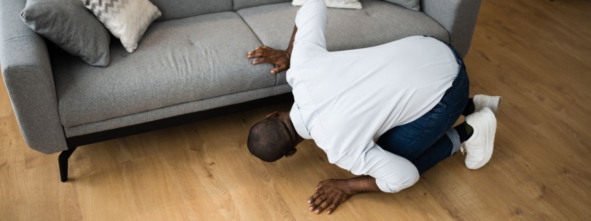 Man looking under couch for keys