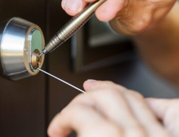 closeup of locksmith hands using pick tools to open locked door