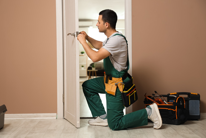 Male worker with screwdriver repairing door